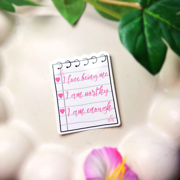


Small sticker as a notepad with affirmations on a light surface with green leaves in the background